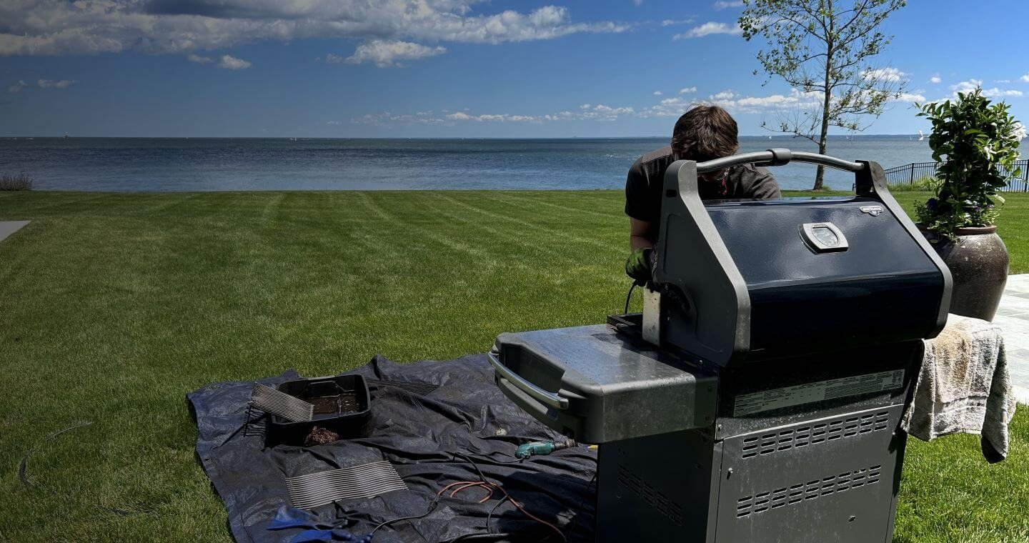 Technician servicing a grill on a waterfront lawn in Fairfield County